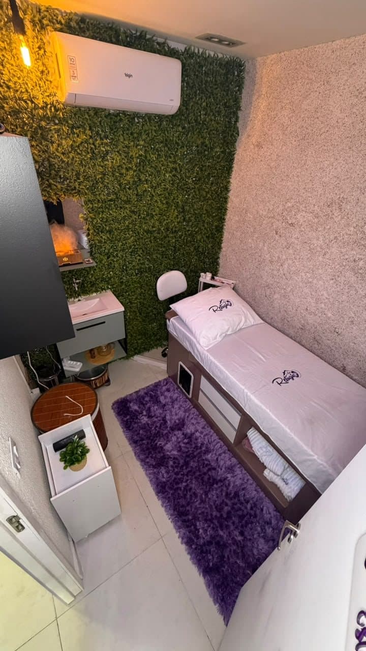 Sala de estética com parede verde, maca e cadeira de atendimento
