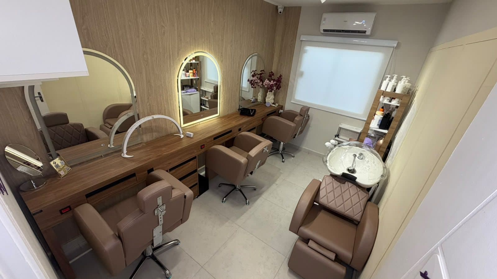 Estações de cabelo com espelhos iluminados e poltronas confortáveis